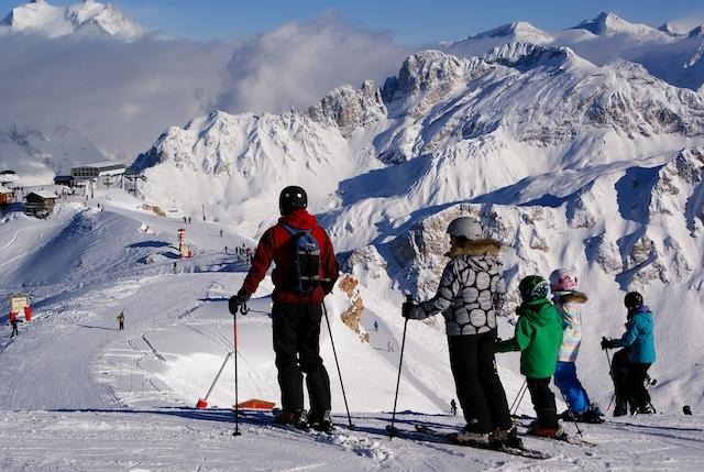 Gezin met kinderen in skikleding geniet van wintersport in de Alpen
