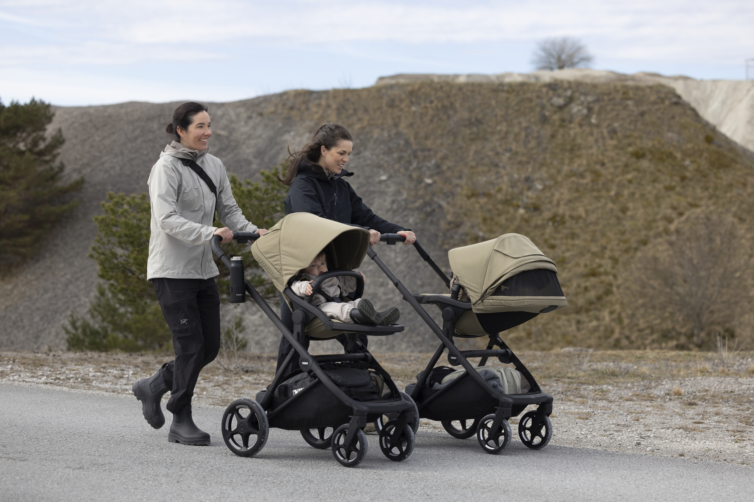 ouder wandelt met Thule Charm kinderwagen met baby in wieg