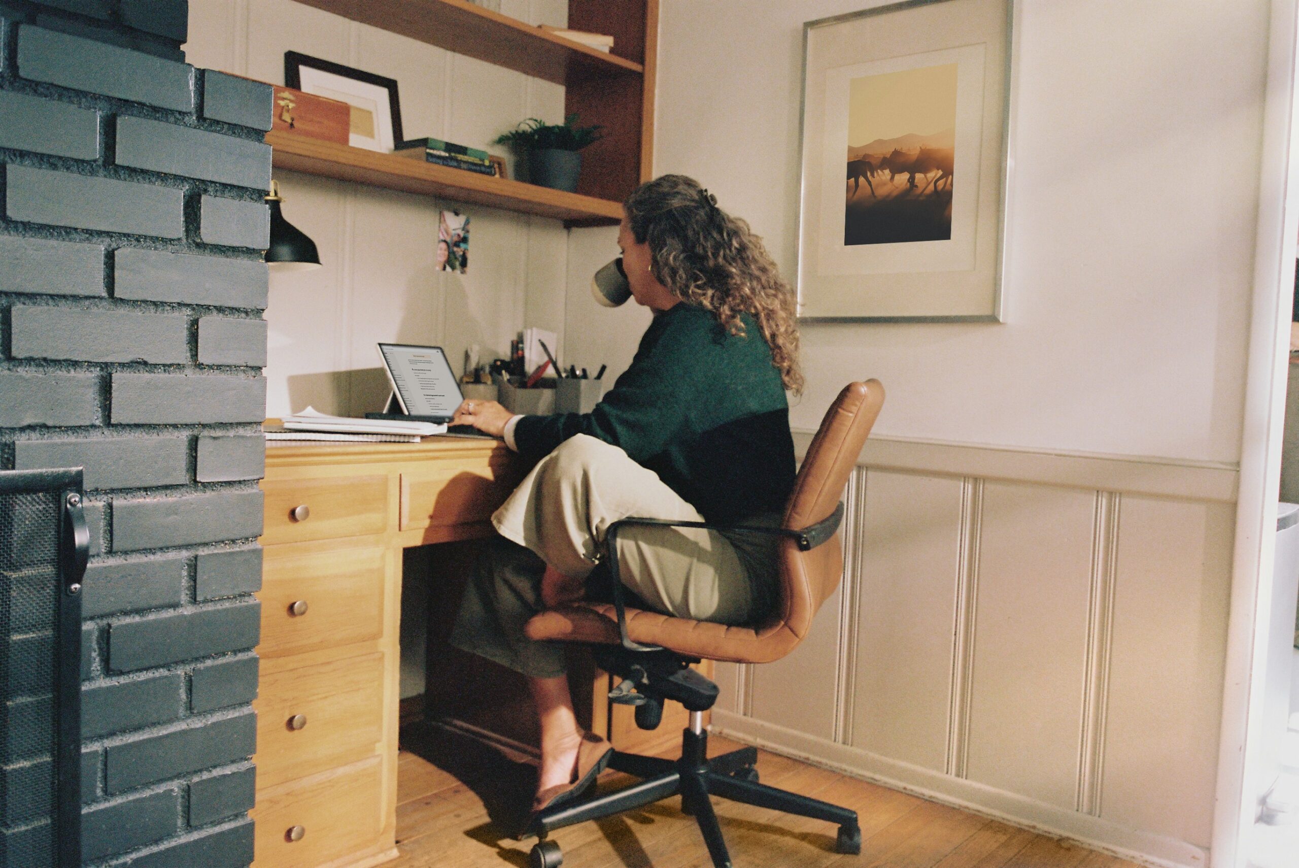 Moeder werkt thuis aan bureau met laptop en koffie